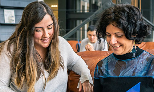 Two researchers looking at laptop and smiling