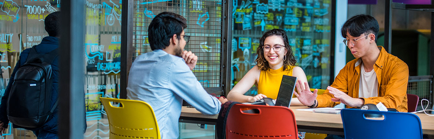 Three researchers sat at a table, talking and smiling