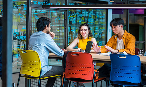 Three researchers looking at laptop and smiling